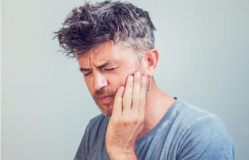 man holding his jaw with TMJ disorder pain