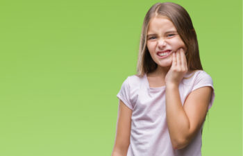 young girl holding her jaw in pain with a dental emergency