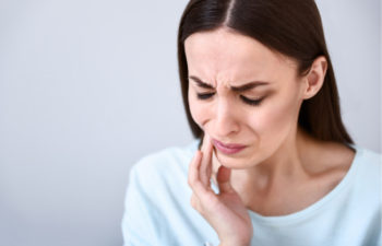 woman holding her jaw with painful gums