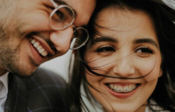 young couple wearing different kinds of braces smile at each other