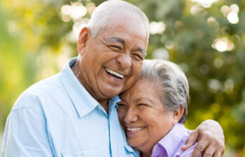 senior couple hug and smile after learning about the benefits of dental implants