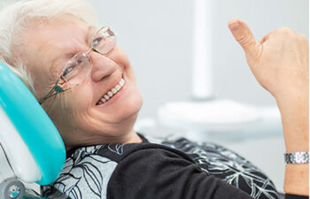 senior woman gives a thumbs up sitting in the dentist chair after learning about diabetes and oral health