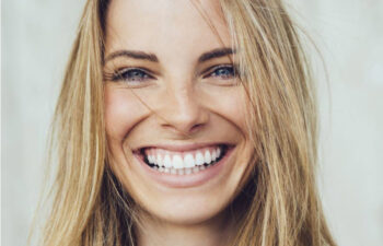 blond woman smiles showing off her porcelain veneers