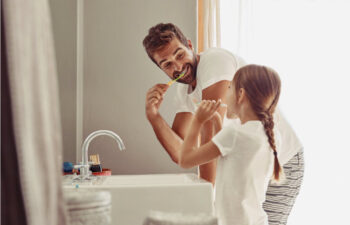 father and young daughter brushing their teeth together