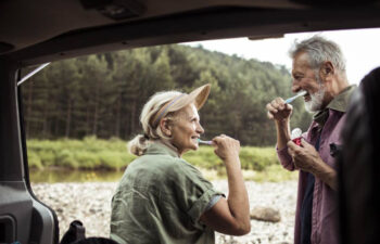 senior couple brush their teeth together while camping