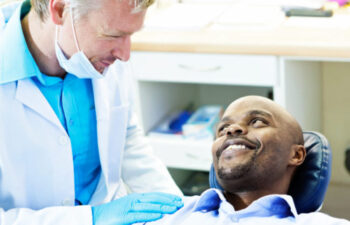 man in the dentist chair chats with the dentist about his dental implants