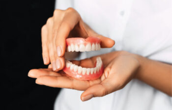 hands holding a set of dentures