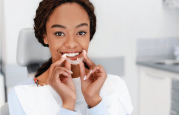 young woman inserts her clear aligner to straighten her teeth